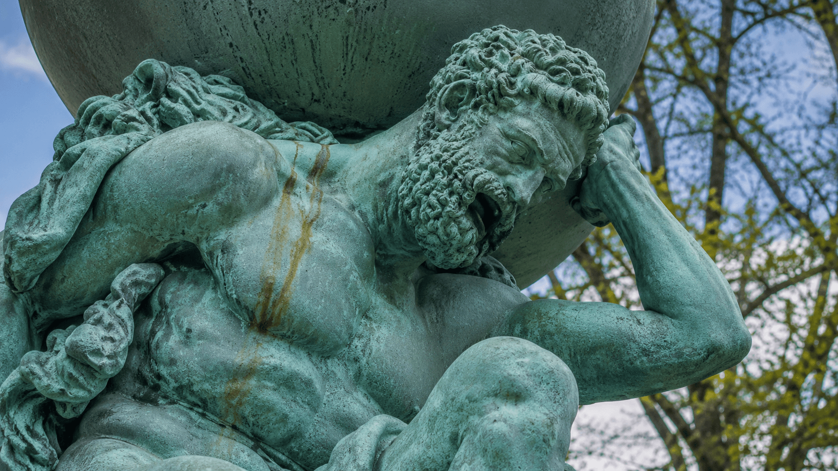 A weathered statue carrying a large globe.